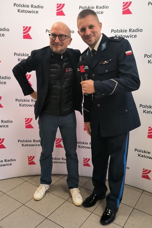 na zdjęciu mężczyzna stojący obok policjanta, za nimi ścianka z napisami Polskie Radio Katowice.