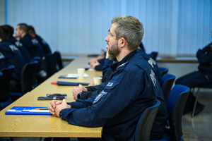 Zdjęcie przedstawia: policjantów siedzących w ławkach.