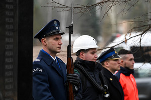 Na zdjęciu zbliżenie na policjanta  i strażaka mundurach galowych oraz ratownika górniczego i ratownika medycznego, pełniących wartę przy pomniku