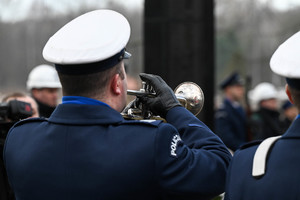 Na zdjęciu policjant w mundurze galowym grający na trąbce