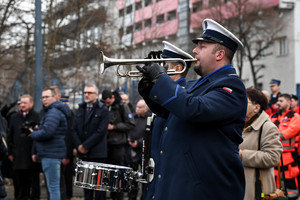 Na zdjęciu policjant w mundurze galowym grający na trąbce