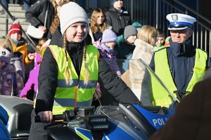 dziewczynka siedzi na motorze policyjnym obok policjant