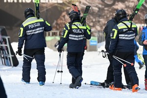 policyjni narciarze idą po śniegu niosąc narty