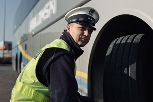 na zdjęciu policjant sprawdzający koło autobusu