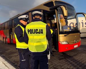 Zdjęcie przedstawia policjantów ruchu drogowego w tle autobus