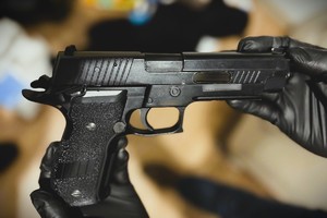 na zdjęciu dłonie osoby trzymające pistolet