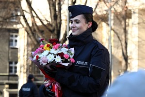 Zdjęcie policjantki w mundurze, która trzyma w rękach bukiet kwiatów