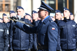 dowódca uroczystości maszeruje z szablą przed kompaniami policjantów mających ślubowanie