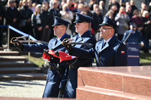 zbliżenie na trzech policjantów z kompanii honorowej którzy niosą flagę państwową