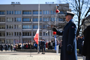 policjant z orkiestry policyjnej w tle pomnik oraz goście uroczystości