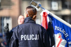 zdjęcie kolorowe policjantki stojącej tyłem składa ślubowanie widoczny również sztandar policji w tle mnie wyraźni pozostali policjanci