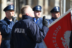 zbliżenie na policjanta składającego ślubowanie widoczny sztandar policji w tle pozostali policjanci