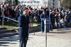 zdjęcie wojewody śląskiego w czasie przemówienia w tle za nimi policjanci i zaproszeni goście, którzy są mniej widoczni