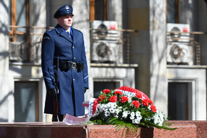 na pierwszym planie wieniec w tle stopi policjant z warty honorowej