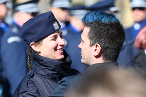 zbliżenie na policjantkę która się uśmiecha gratulacje składa jej bliska osoba i przytula ją