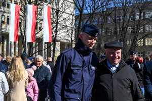 zbliżenie na policjanta obok którego stoi starszy mężczyzna członek rodziny obaj się uśmiechają