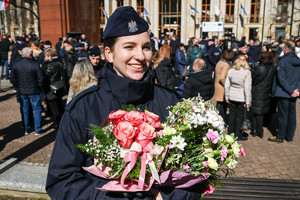 zbliżenie policjantki która trzyma dwa bukiety kwiatów