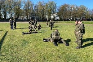 Zdjęcie przedstawia grupę żołnierzy oraz umundurowanego policjanta wykonujących ćwiczenia podczas szkolenia.