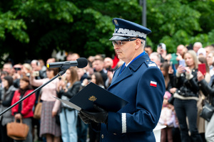 Na zdjęciu Komendant Wojewódzki Policji w Katowicach stojący przed mikrofonem z granatową teczką ręku z symbolem godła polskiego.
