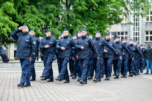 Na zdjęciu policjant oddający honor i idący za nim nowo przyjęci policjanci