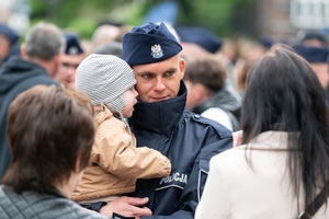 Na zdjęciu policjant trzymający na rękach małe dziecko