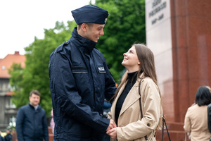 Na zdjęciu policjant i dziewczyna trzymający się za ręce i patrzący na siebie