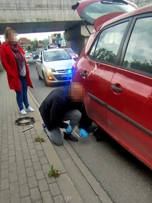 Policjant w cywilu podczas wymiany koła w samochodzie