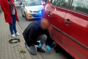 Policjant w cywilu podczas wymiany koła w samochodzie