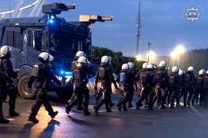 Maszerujący policjanci w umundurowaniu i w kaskach