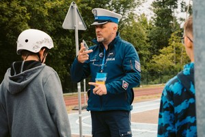 Na zdjęciu umundurowany policjant rozmawiający z dziećmi