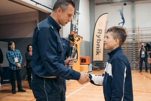 Na zdjęciu umundurowany policjant wręczający dziecku puchar.