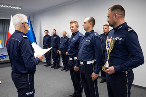 na zdjęciu policjanci pod ścianą z nagrodami