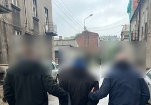 Dwaj policjanci w cywilu prowadzą ulicą zatrzymanego mężczyznę