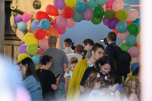 Zdjęcie przedstawia grupę dzieci przechodzącą przez wieniec z balonów