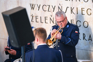Zdjęcie przedstawia policjanta grającego na instrumencie