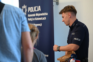 Zdjęcie przedstawia policjanta stojącego bokiem