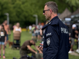 Zdjęcie przedstawia policjanta stojącego bokiem