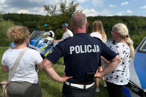 Zdjęcie przedstawia policjanta oraz dwie kobiety stojące tyłem