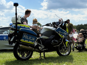 Zdjęcie przedstawia ojca trzymającego córkę która siedzi na policyjnym motocyklu