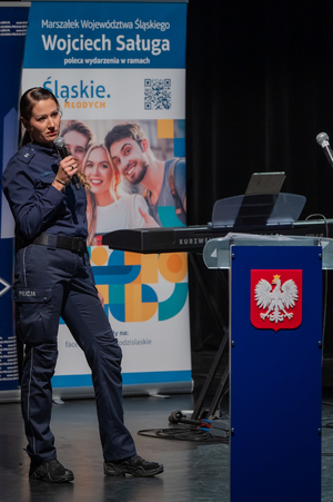 Zdjęcie przedstawia policjantkę trzymającą mikrofon