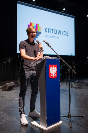 Zdjęcie przedstawia mężczyznę mówiącego do mikrofonu
