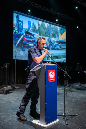 Zdjęcie przedstawia policjanta mówiącego do mikrofonu