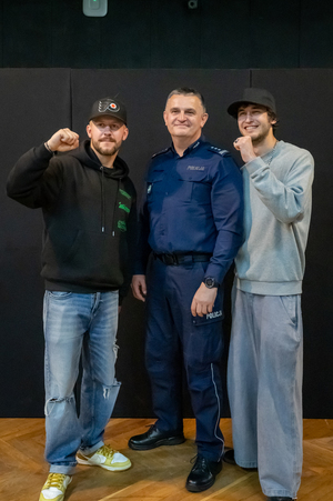 Zdjęcie przedstawia dwóch mężczyzn oraz policjanta