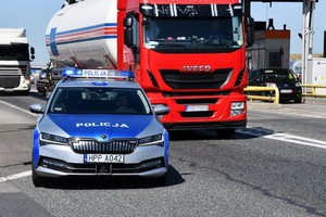 Na zdjęciu widać policyjny radiowóz, samochody ciężarowe, a w tle autostradę.