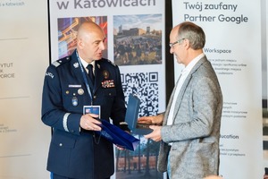 Zdjęcie przedstawia nadinspektora doktora Rafała Kochańczyka, w umundurowaniu rozmawiającego z mężczyzną w garniturze.