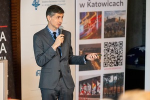 Zdjęcie przedstawia mężczyznę przemawiającego podczas konferencji.
