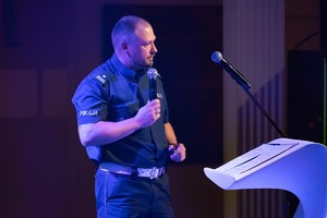 Zdjęcie przedstawia: policjanta ruchu drogowego z mikrofonem.