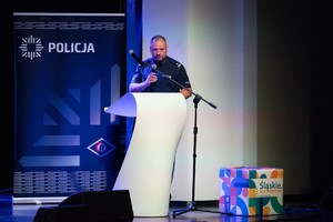 Zdjęcie przedstawia: policjanta przy mównicy.