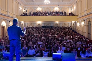 Zdjęcie przedstawia: policjanta podczas przemówienia, z tyłu licznie zgromadzona widownia.