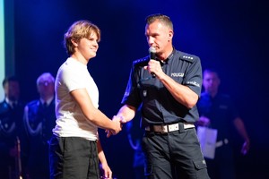 Zdjęcie przedstawia: policjanta, który ściska dłoń nastolatka.